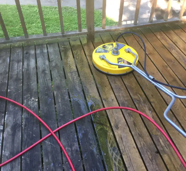 A yellow and black power washer on top of a wooden deck.